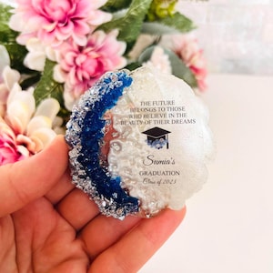 May include: White and blue agate coaster with a graduation quote: "The future belongs to those who believe in the beauty of their dreams."  The coaster also includes the text "Sumia's Graduation Class of 2023".