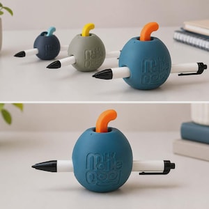 Peut inclure: Trois porte-stylos sphériques bleu foncé, vert sauge et bleu sarcelle, chacun doté d'un sommet incurvé en forme de tige et du texte en relief "make cool". Un stylo blanc avec une pointe et un clip noirs est inséré horizontalement au centre.
