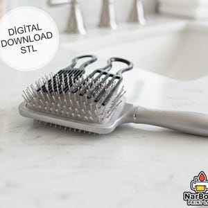 Puede incluir: Un cepillo para el cabello plateado y negro con un mango largo y una cabeza rectangular. Dos peines negros descansan sobre el cepillo. La imagen incluye el texto "DIGITAL DOWNLOAD STL".