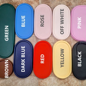 May include: Ten oval-shaped containers in various colors, including green, blue, dark blue, red, yellow, off-white, pink, and black. Each container has a word printed on it, such as "Green", "Blue", "Dark Blue", "Red", "Yellow", "Off White", "Pink", and "Black".
