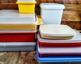 May include: A stack of eight plastic storage containers in various colors, including red, yellow, beige, and blue. The containers are all rectangular and have lids.