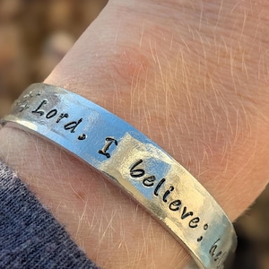 May include: A silver bracelet with the words "Lord, I believe..." engraved on it.