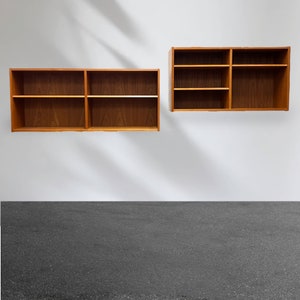 May include: Two wooden wall shelves with three shelves each. The shelves are made of light brown wood and are mounted on a white wall.