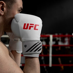 May include: A white boxing glove with black and gray stripes and the word "UFC" in red lettering.