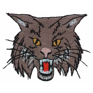 以下が含まれることがあります： 黄色い目をした茶色と白の猫の刺繍パッチ。口は赤く開いていて、歯を見せています。猫の毛並みはステッチで細かく表現されています。
