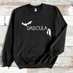 May include: Black sweatshirt with a white bat and the text "DADCULA" printed on the front.