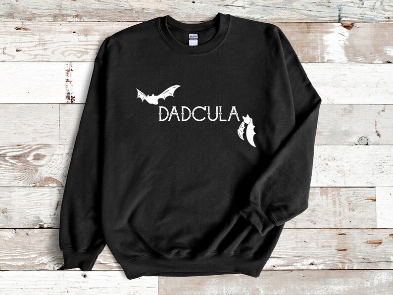 May include: Black sweatshirt with a white bat and the text "DADCULA" printed on the front.