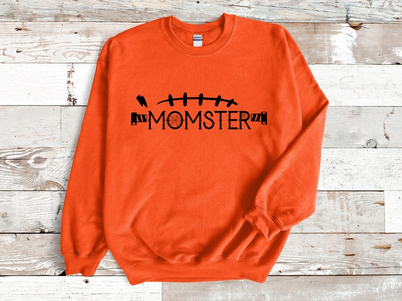 May include: Orange sweatshirt with a black graphic of stitches and the text "MOMSTER".