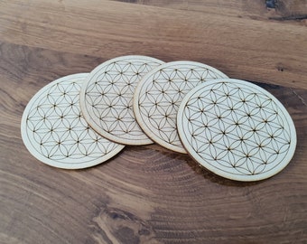 Könnte beinhalten: Vier Untersetzer aus Holz mit einem lasergravierten Lebensblume-Design. Die Untersetzer sind rund und haben eine hellbraune Farbe.