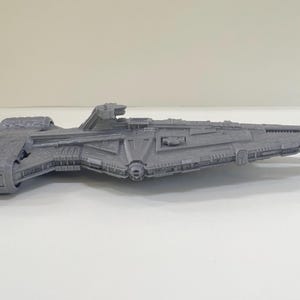 Op de afbeelding: Een grijs, gedetailleerd model van een ruimteschip, met ingewikkelde ontwerpen en een getextureerd oppervlak. Het ruimtevaartuig heeft een lange, slanke romp met diverse uitsteeksels en een duidelijk voorste gedeelte. Het model is waarschijnlijk een verzamelobject.