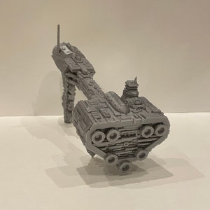 May include: A grey 3D printed model of a spaceship with a long, thin body and a large, round engine section at the rear. The spaceship has a small, rectangular cockpit at the front and a series of small, round windows along the side.