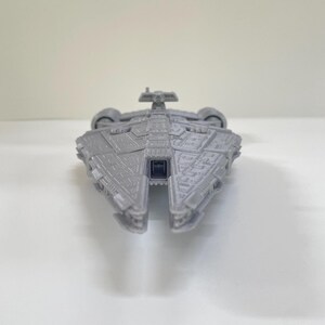 Op de afbeelding: Een grijs model ruimteschip met ingewikkelde details, met een centraal lichaam en vleugelachtige structuren. Het speelgoed ruimteschip is ontworpen met een symmetrische lay-out en lijkt van plastic te zijn. Het model staat tegen een effen witte achtergrond.