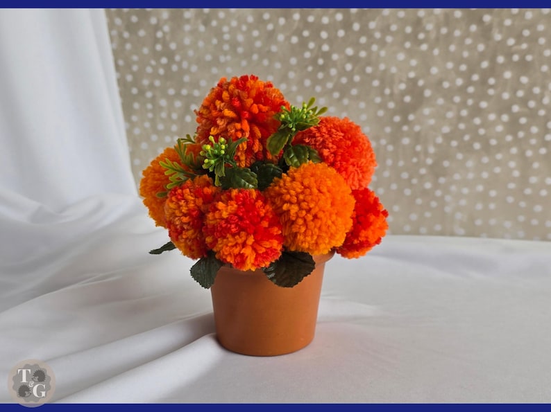 May include: A terracotta pot filled with a bouquet of orange and yellow pom-pom flowers.