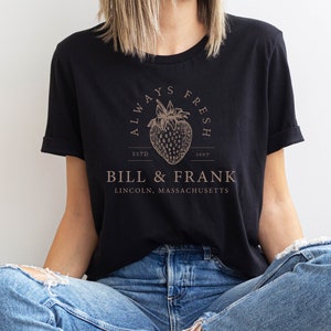 May include: A black t-shirt with a brown graphic of a strawberry and the text "Always Fresh" above the text "Bill & Frank" and "Lincoln, Massachusetts".