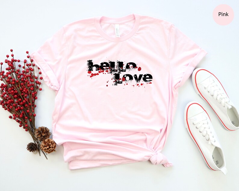 May include: Pink t-shirt with a black graphic that says "hello love" with red splatters.
