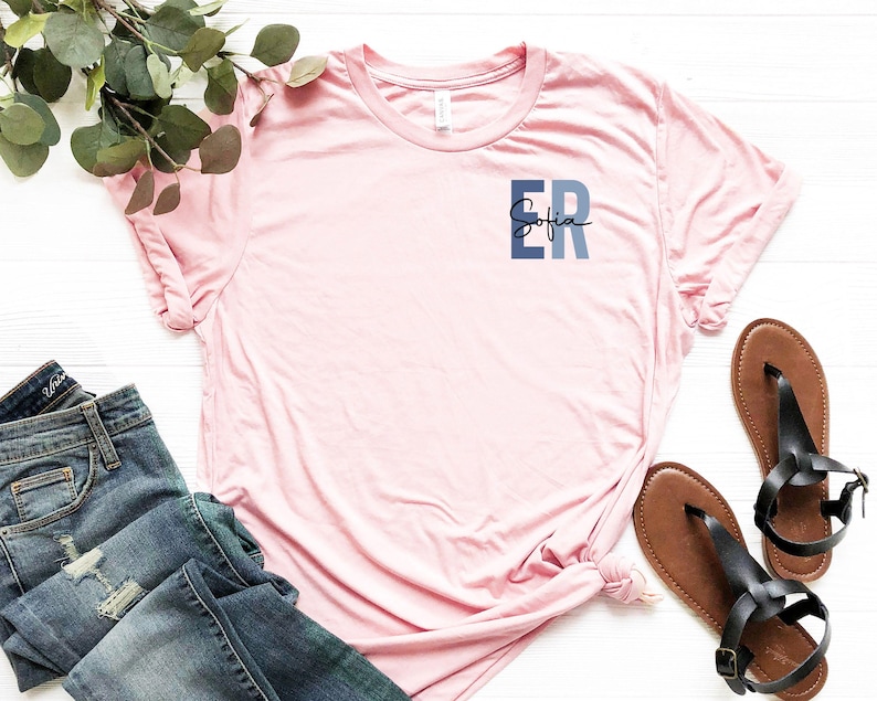 May include: A pink t-shirt with a blue and gray pocket design that says "Sofia ER" on it.
