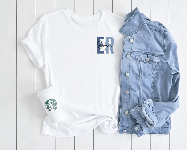 May include: White t-shirt with a blue and white "ER" monogram and the name "Sofia" written in cursive underneath. The t-shirt is paired with a light blue denim jacket.