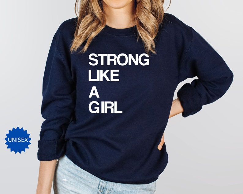 May include: A navy blue sweatshirt with the text "STRONG LIKE A GIRL" printed in white on the front.