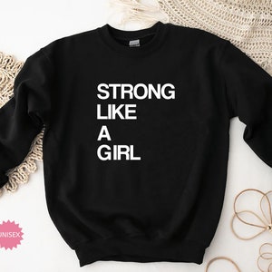 May include: Black sweatshirt with the text "STRONG LIKE A GIRL" in white.