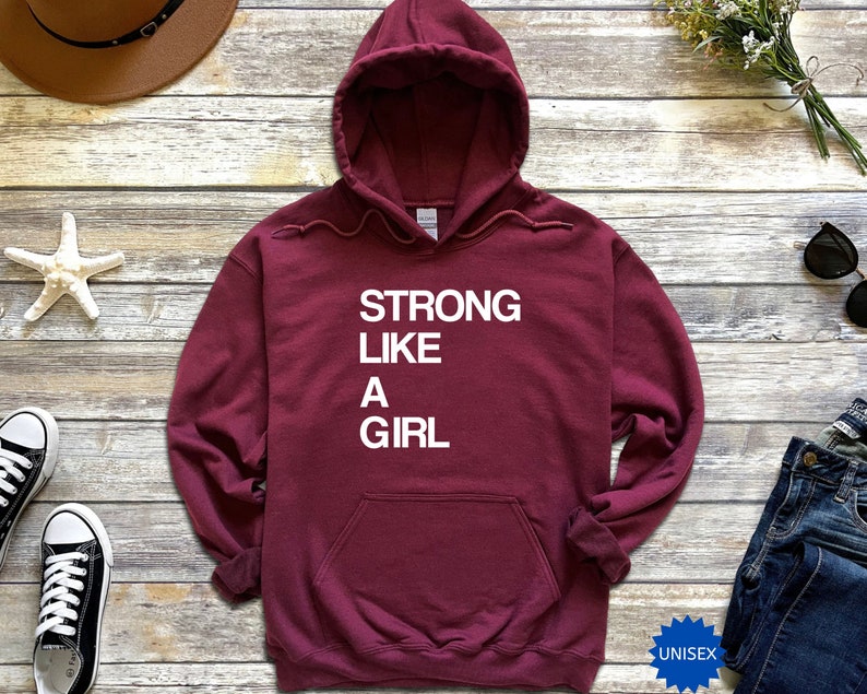May include: Burgundy unisex hoodie with the text "STRONG LIKE A GIRL" in white lettering.