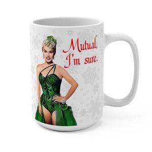 May include: White ceramic mug with a snowflake pattern. The mug features a cartoon image of a woman in a green dress and the text "Mutual, I'm sure."