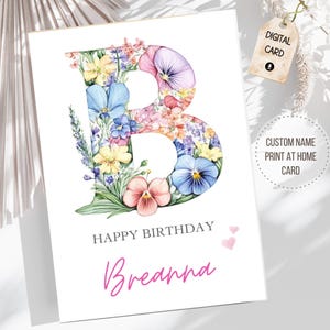 May include: A white birthday card featuring a floral "B" design in shades of blue, pink, and yellow. The card includes the text "Happy Birthday" and a name in pink script. A tag reads "Digital Card".