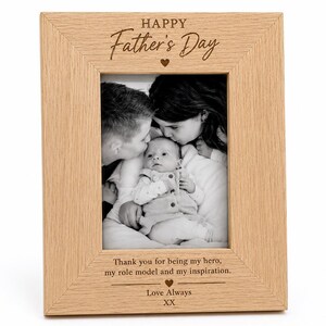 May include: A light-colored wooden picture frame with a family photo. The frame has the words "HAPPY Father's Day" engraved at the top, and a message at the bottom that reads "Thank you for being my hero, my role model and my inspiration. Love Always XX."