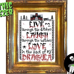 May include: A framed cross-stitch design with a gothic theme. The design features a castle, bats, and the text "LIVE through the ditches LAUGH through the witches LOVE in the back of my DRAGULA".