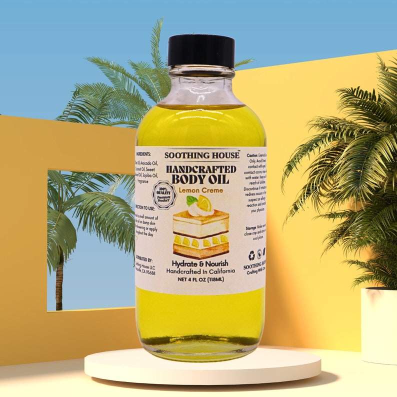 May include: A glass bottle containing yellow body oil, labelled "SOOTHING HOUSE HANDCRAFTED BODY OIL Lemon Creme". The bottle holds 118ml of oil. The background features palm trees and a yellow and blue backdrop, creating a tropical feel.