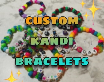 Puede incluir: Primer plano de varios brazaletes kandi personalizados de colores con cuentas de letras. Los brazaletes están hechos con cuentas de plástico de diferentes colores y tienen palabras como "KIND" y "GAY".