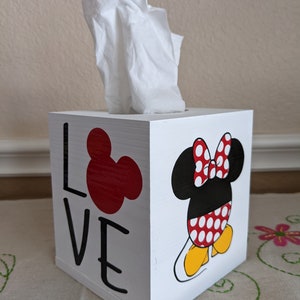 May include: White wooden tissue box cover with a red Mickey Mouse head and the word "LOVE" on one side and a black and white Minnie Mouse with a red bow and polka dot dress on the other side.