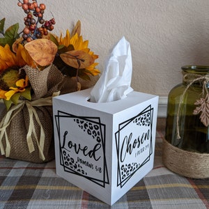 May include: White wooden tissue box cover with black and white leopard print design. The cover has the words "Loved Romans 5:8" and "Chosen 1 Peter 2:9" on it.