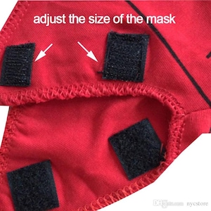 Op de afbeelding: Rode stoffen masker met verstelbare klittenbandriempjes. De tekst "adjust the size of the mask" is op de stof gedrukt.