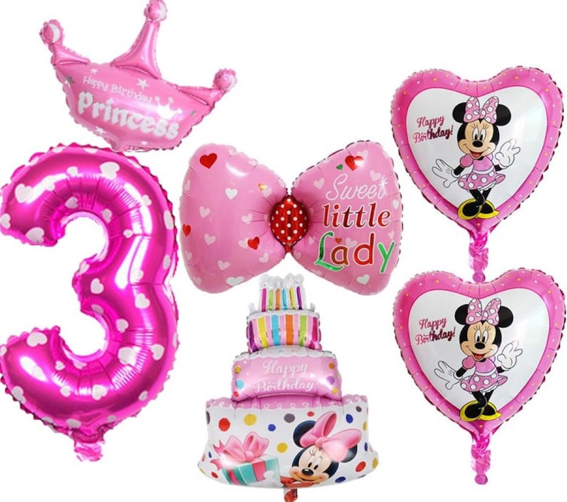 May include: Pink and white balloon decorations for a birthday party. The balloons include a number 3, a bow, a cake, a crown, and two heart-shaped balloons with Mickey Mouse characters. The balloons have the text "Happy Birthday!" and "Sweet little Lady".