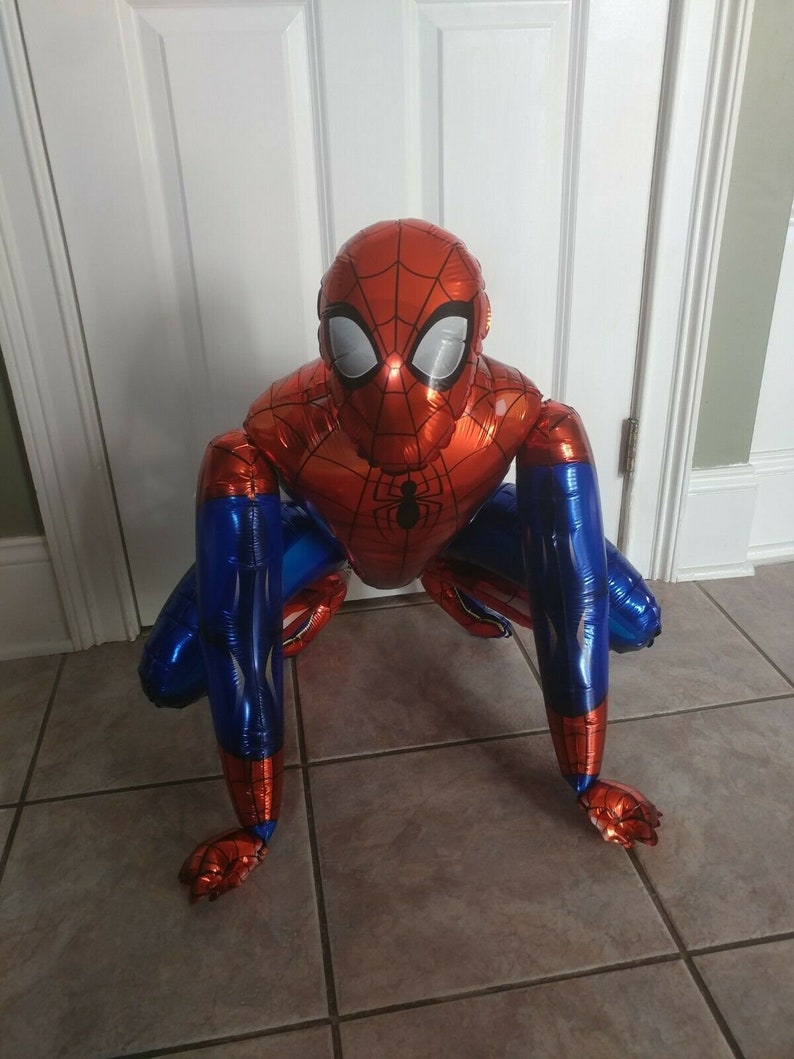 K&ouml;nnte beinhalten: Ein roter und blauer Spider-Man-Ballon in einer hockenden Pose. Der Ballon besteht aus gl&auml;nzendem, metallischem Folienmaterial.
