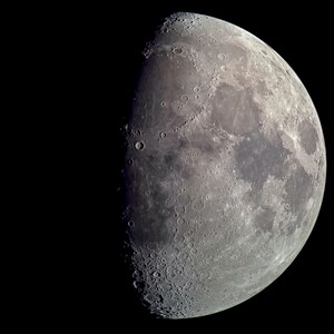 以下が含まれることがあります： 三日月形の月のクローズアップ画像で、クレーターや暗い領域のある表面が示されています。月は右側が照らされ、左側が影になっています。