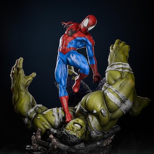 Puede incluir: Una figura de acción de Spider-Man roja y azul está de pie sobre una figura de acción de Hulk verde. Hulk está acostado de espaldas con los brazos extendidos. Las figuras están posadas en una escena de acción dinámica.