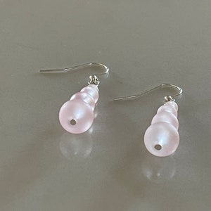 以下が含まれることがあります： ピンクのガラスビーズが付いたシルバーのドロップイヤリングのペア。ビーズは、一番下のビーズが最も大きく、段階的にサイズが小さくなっています。