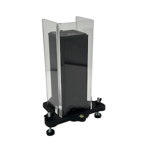 May include: A black speaker is enclosed in a clear acrylic case with a black base and adjustable feet. The base has a level indicator.