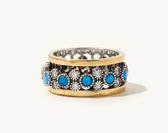 May include: A gold and silver ring with a band of blue and white stones.