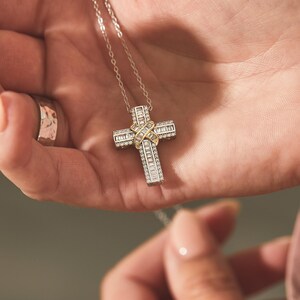 Puede incluir: Un collar de cadena de plata con un colgante de cruz de oro y plata incrustado con piedras de circonita c&uacute;bica transparentes.