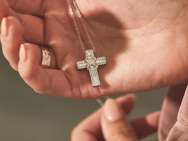 Puede incluir: Un collar de cadena de plata con un colgante de cruz de oro y plata incrustado con piedras de circonita c&uacute;bica transparentes.