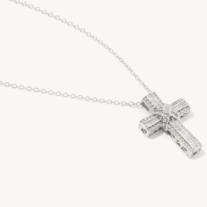 Puede incluir: Un collar de cadena de plata con un gran colgante de cruz engastado con diamantes.