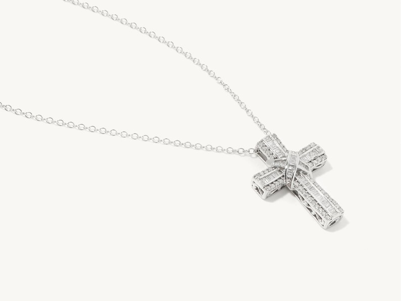 Puede incluir: Un collar de cadena de plata con un gran colgante de cruz engastado con diamantes.