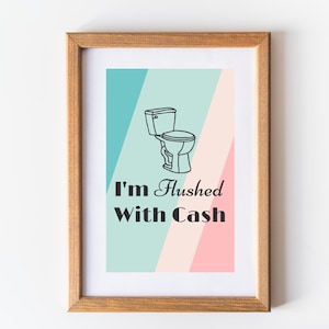 May include: A framed print with a light blue, pink, and white background. A black and white illustration of a toilet is in the center of the print. The text "I'm Flushed With Cash" is below the illustration.