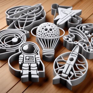 May include: A set of eight gray plastic cookie cutters shaped like an astronaut, a hot air balloon, a rocket ship, a spaceship, a galaxy, a star, a swirl, and a flower.