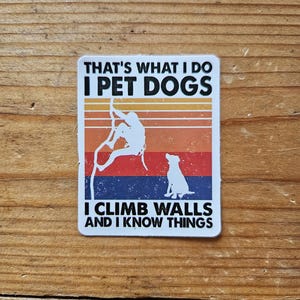 Op de afbeelding: Een witte sticker met een retro-ontwerp met een silhouet van een persoon die klimt met een hond eronder. De tekst luidt "That's what I do I pet dogs I climb walls and I know things."