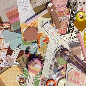 May include: A collection of colorful stationery items, including bookmarks, stickers, washi tape, and a ruler. The items feature various designs, including animals, flowers, and geometric patterns. The text "ONE POINT MARKER" and "CAFE LATTE" are visible on some of the items.