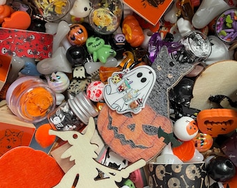 Puede incluir: Una colección de suministros de artesanía con temática de Halloween, que incluye recortes de madera de una bruja, una calabaza y un fantasma, junto con cinta con estampado de calaveras en blanco y negro, cuentas naranja y negras y un pequeño frasco de vidrio lleno de confeti naranja y negro.