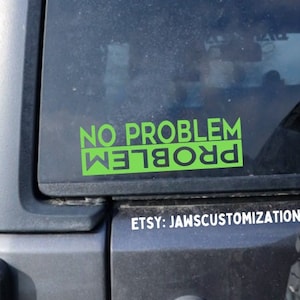 Könnte beinhalten: Ein grüner "NO PROBLEM" Aufkleber ist auf einer Fahrzeugscheibe angebracht. Der Text ist fett und ohne Serifen. Unter dem Aufkleber steht der Etsy-Shop-Name "ETSY: JAWSCUSTOMIZATION" in weißer Schrift.